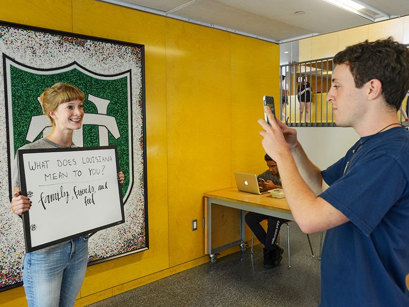 Student takes photo of student posing at photo op wall